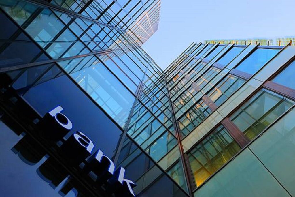 Bank corporate finance building seen from below. The sign "bank" visible close. Sky reflecting in the glass facade. More Facade pictures below